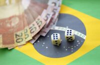 Small dice cubes with brazilian money bills on flag of Brasil Republic. Concept of luck and gambling in Brasil