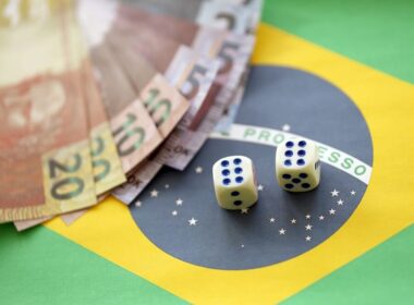 Small dice cubes with brazilian money bills on flag of Brasil Republic. Concept of luck and gambling in Brasil